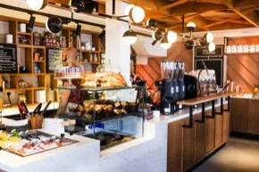 Interior of 39 Steps Coffee Haus, Soho: marble counter, pastry cabinet and pendant globe lights